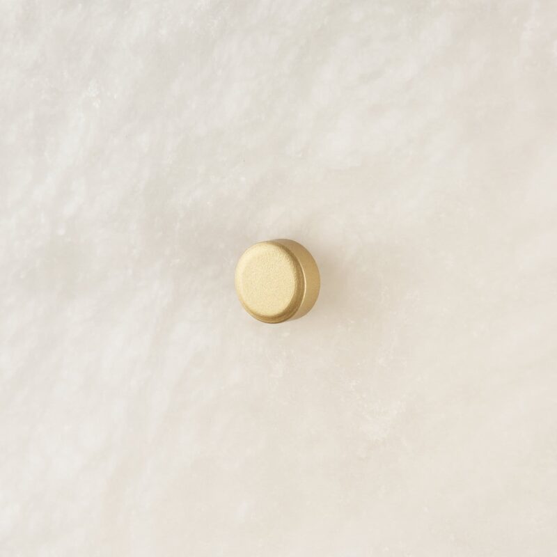Sleek gold button against a soft textured background, highlighting modern elegance and simplicity.