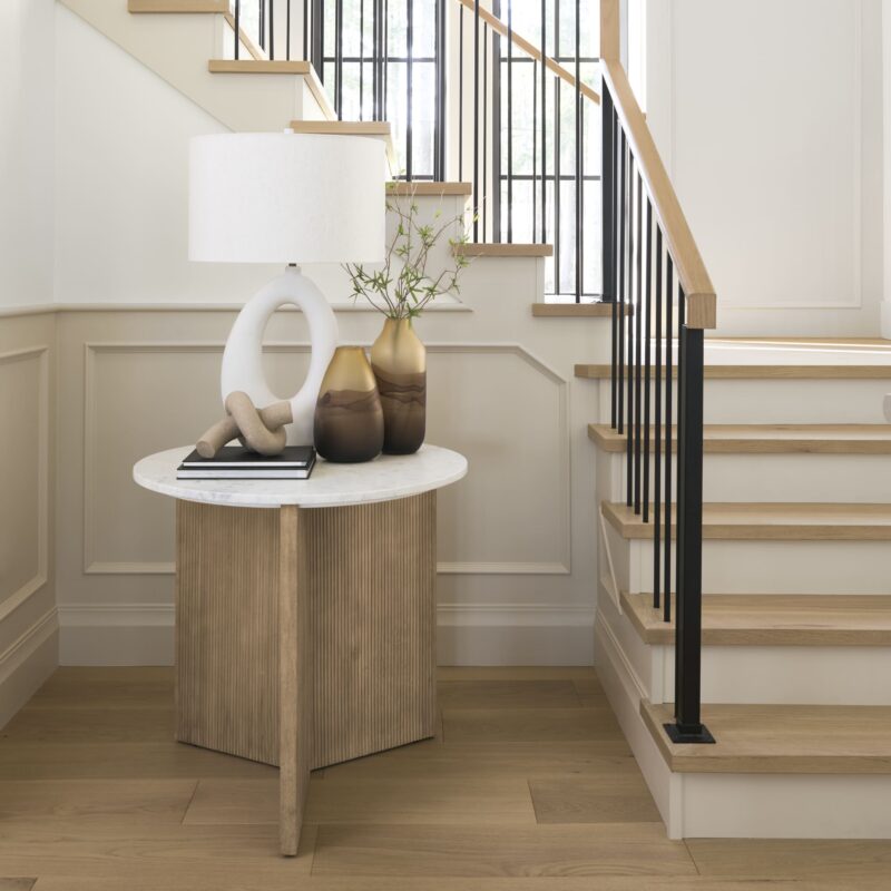 Elegant modern entryway with a wooden staircase, marble side table, and natural accents.