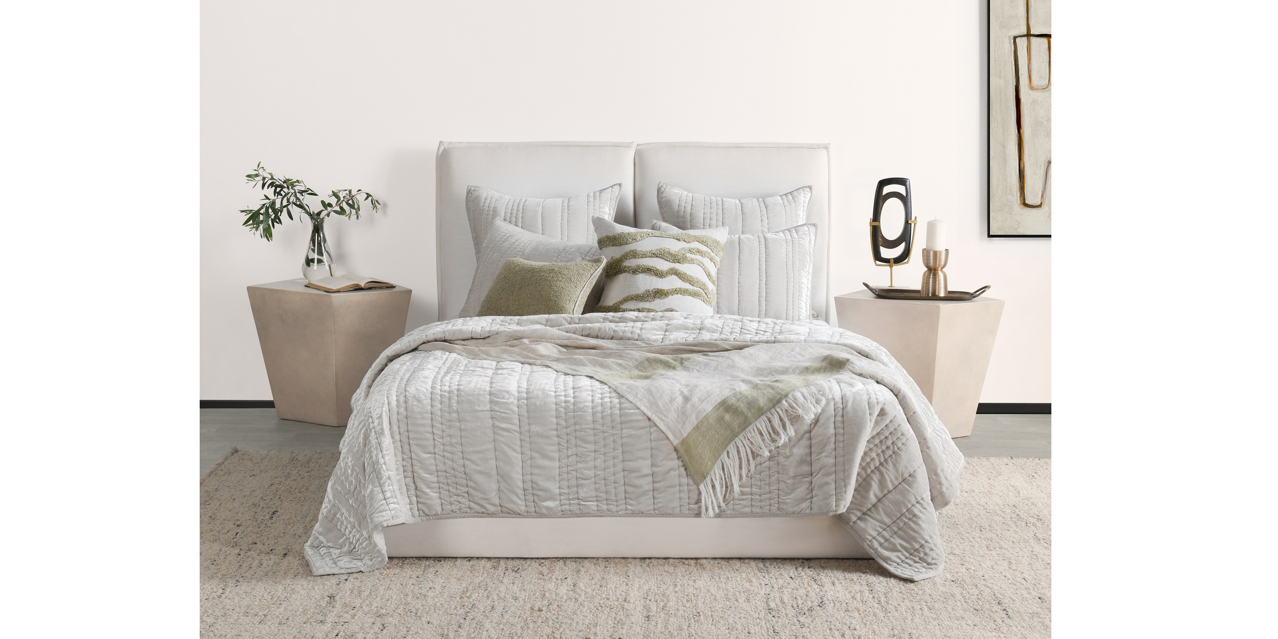 Stylish modern bedroom with gray bedding, olive accent pillow, chic nightstands, and serene artwork.