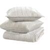 Elegant striped pillows atop a cozy blanket create a serene bedding display in soft tones.