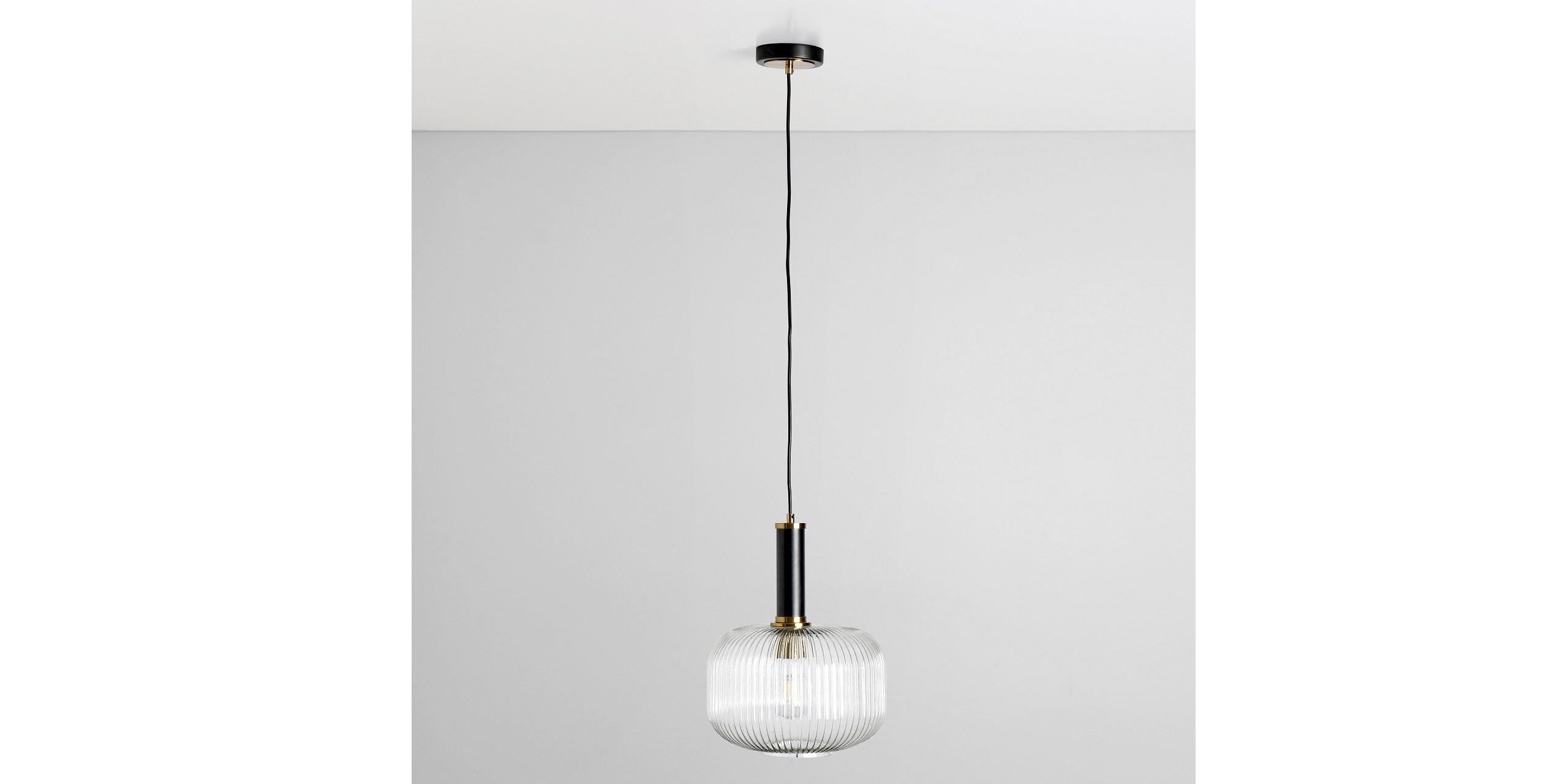 Stylish fluted glass pendant light with black metal canopy and warm golden accents for modern decor.