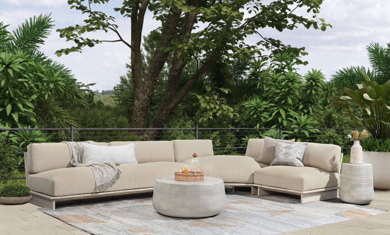 Stylish outdoor living area with a beige sectional sofa, round coffee table, and lush greenery.