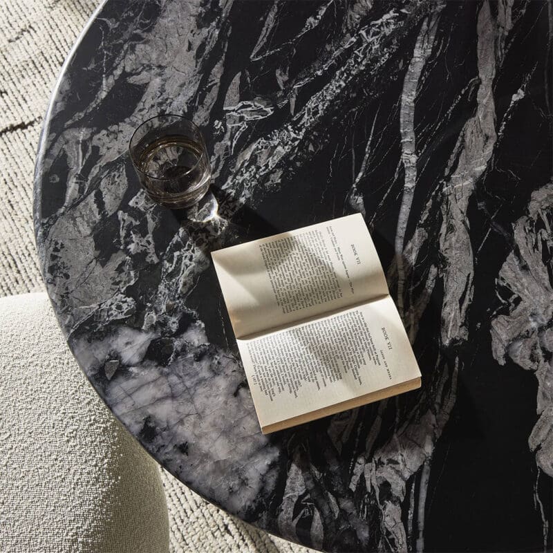 Stylish black marble tabletop with a book and glass, ideal for serene reading moments.