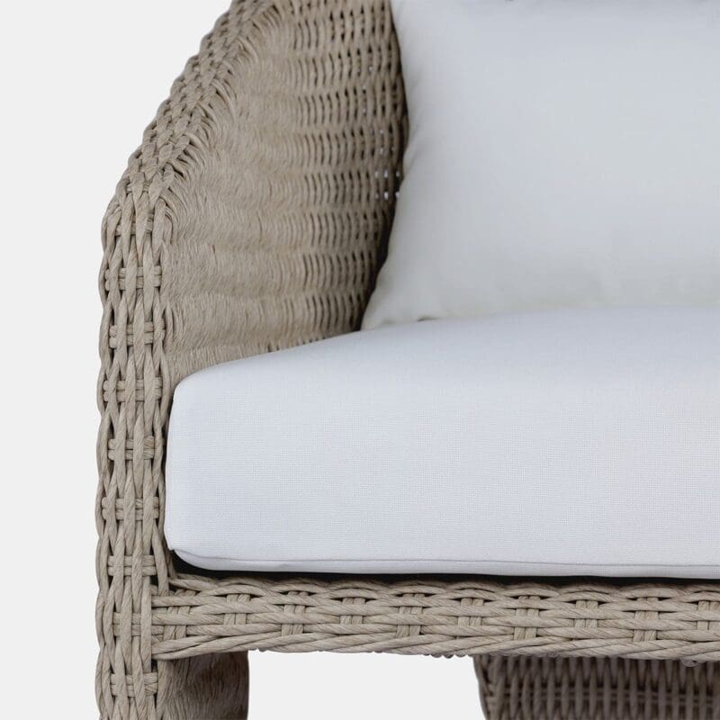 Cozy wicker chair with plush white cushion for stylish outdoor and indoor relaxation.