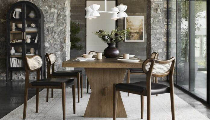 Stylish modern rustic dining area with light wood table, woven chairs, and floral chandelier.
