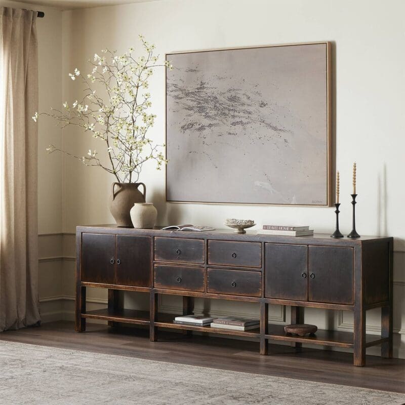 Elegant room with dark wooden console, abstract art, floral arrangement, and natural light.