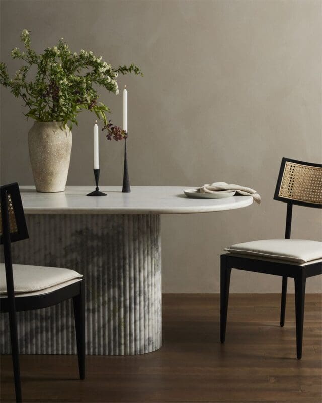 Serene minimalist dining room with an oval marble table, elegant chairs, and floral centerpiece.