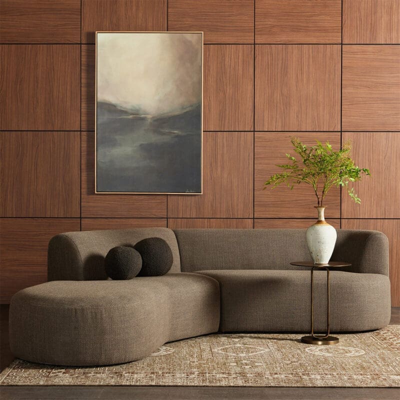 Cozy modern living room with a curvy brown sofa, abstract art, and greenery accents.