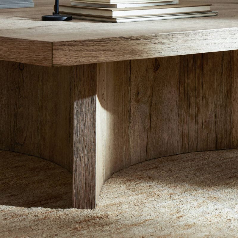 Stylish minimalist coffee table in natural wood with stacked books and cozy rug accents.