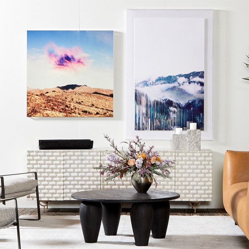 Stylish living room with vibrant landscape art, chic console table, and cozy leather sofa.
