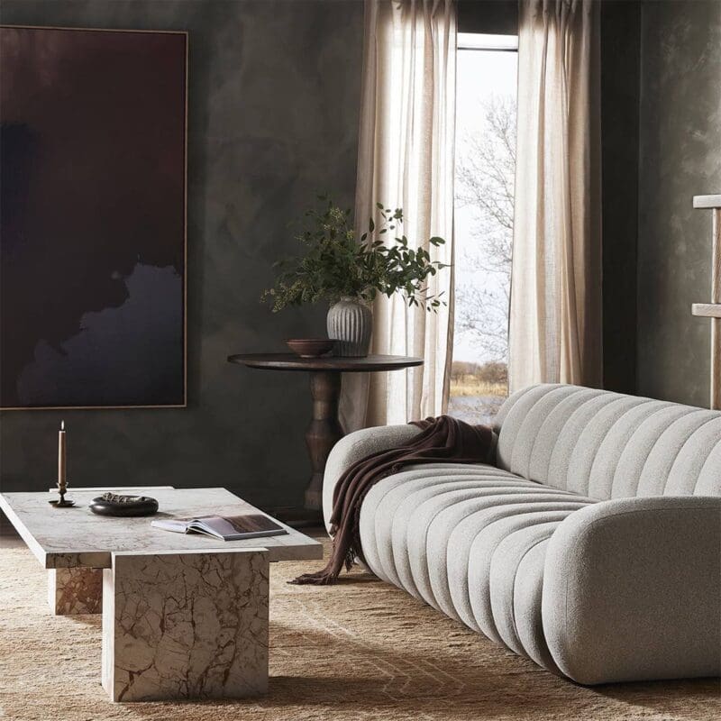 Contemporary living room with plush sofa, marble coffee table, and natural greenery accents.