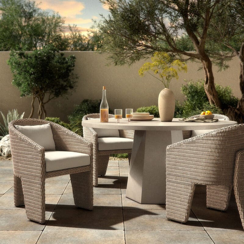 Chic outdoor dining area with a stone table, woven chairs, and lush greenery ambiance.