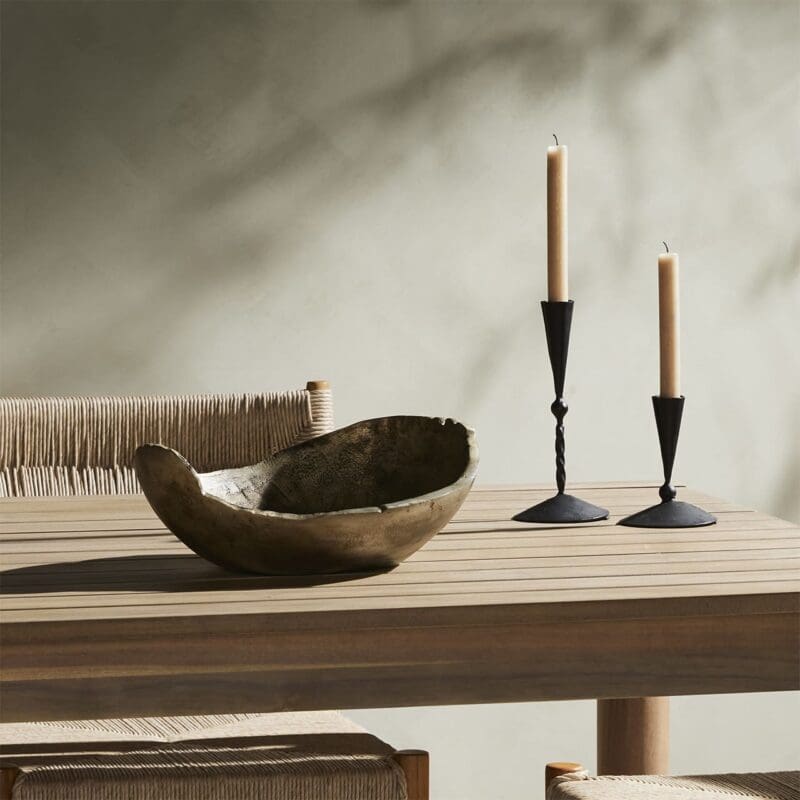 Warm wooden table setting with a dark bowl and elegant black candle holders.