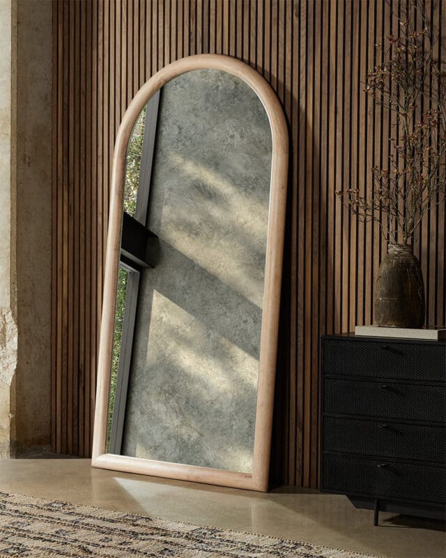 Sleek arched mirror in a warm, nature-inspired interior with modern accents and cozy textures.