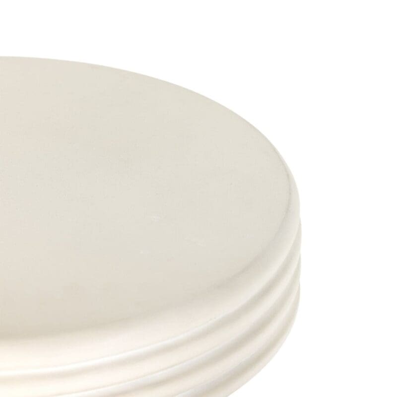 Minimalist cream circular stool with textured edges, perfect for versatile interior design.