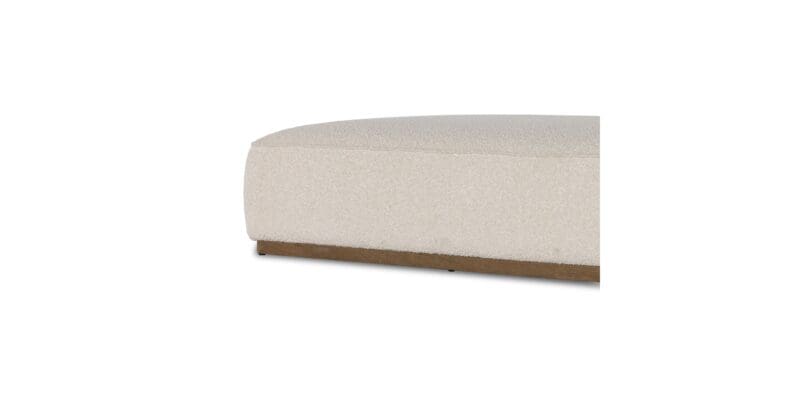 Contemporary soft sofa cushion in light fabric with rounded edges and wooden base.