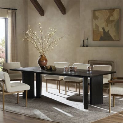 Contemporary dining area with elegant table, light chairs, and natural centerpiece under soft sunlight.