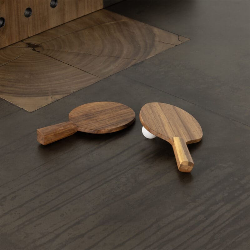 Elegant wooden table tennis paddles and a ball on a dark wooden floor, ready for play.
