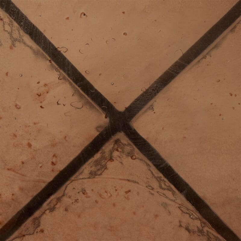 Close-up of warm, rustic tile surface with speckles and dark grout, ideal for cozy interiors.