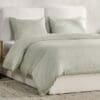 Tranquil bedroom with elegant light green bedding and a sleek white bed frame for relaxation.