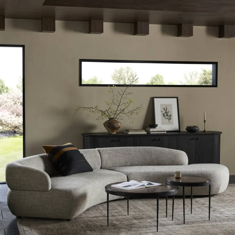 Stylish minimalist living room featuring a sectional sofa, round coffee tables, and natural light.