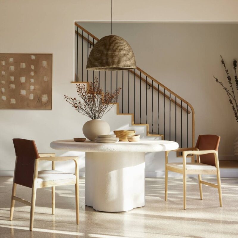 Modern minimalist dining area with a round table, textured base, and natural elements.