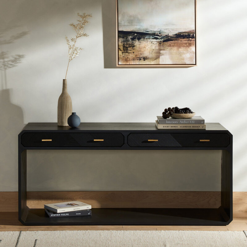 Modern black console table with elegant decor, featuring a vase, books, and abstract wall art.