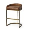 Sleek bar stool with brown leather cushion and brass frame for modern interiors.